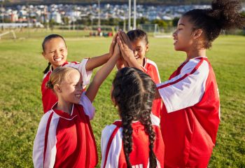 Children high five on a soccer field.